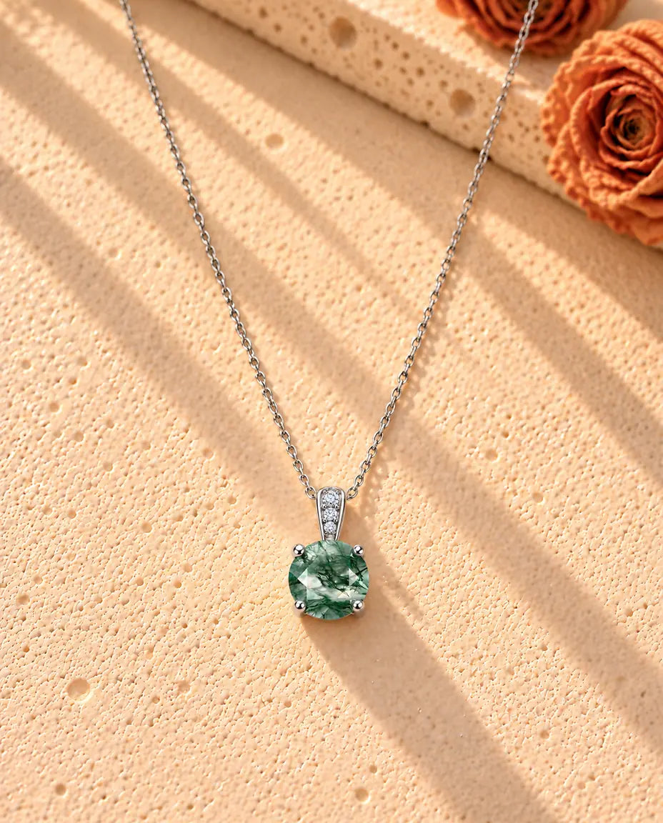 Round Moss Agate Solitaire Necklace in 925 Sterling Silver - the whole necklace laid out in a long V on a cream textured surface