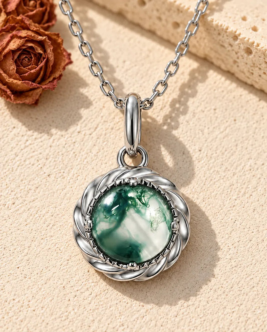 Round Moss Agate Pendant Necklace in 925 Sterling Silver - lying on a cream textured surface beside a travertine block
