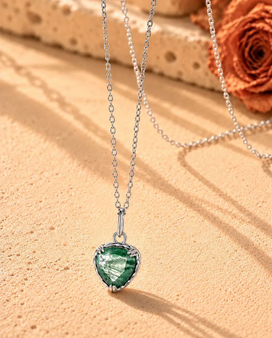 Heart Moss Agate Pendant Necklace in 925 Sterling Silver - seen at an angle on a cream textured surface