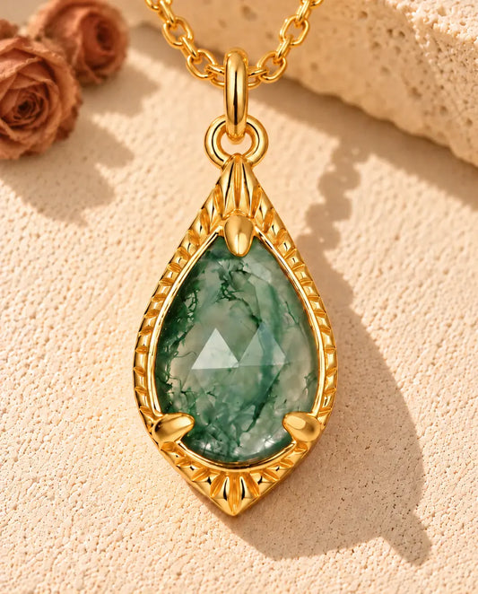 Teardrop Moss Agate Necklace in 10K Gold Plated 925 Sterling Silver - lying on a cream textured surface beside a travertine block