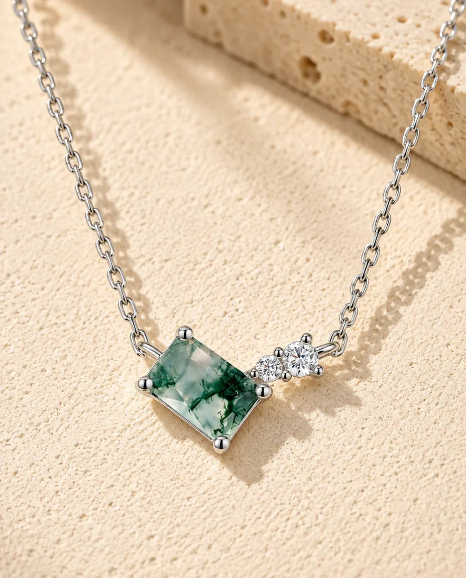 Moss Agate Bar Necklace in 925 Sterling Silver - lying on a cream textured surface beside a travertine block