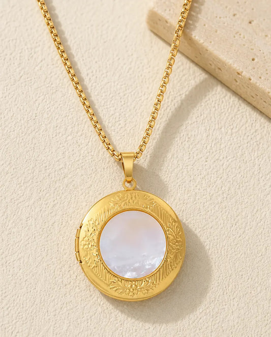 Gold round photo locket necklace with a white mother of pearl center and embossed floral border
