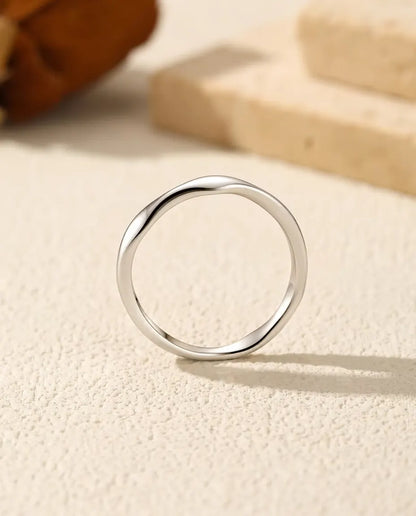 Wavy Band Ring in 925 Sterling Silver - seen straight on, standing on a cream textured surface
